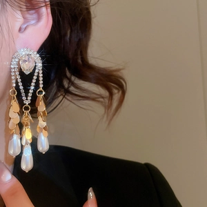 Detailed close-up of long gold-plated drop earrings with rhinestones and teardrop pearls