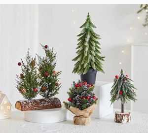 Close-up of assorted mini Christmas trees with pine cones, berries and snow on white base