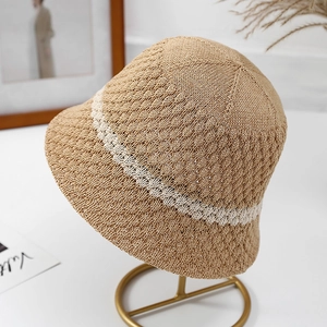 Women's khaki knit bucket hat with white wavy stripes on a stylish gold display stand