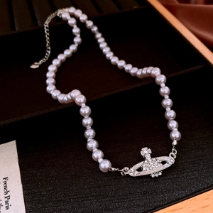 Detailed macro view of Saturn pendant on pearl necklace with sparkling white rhinestones