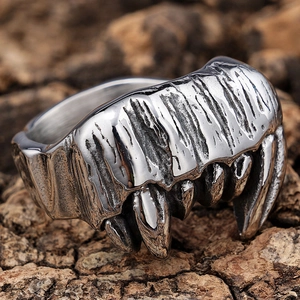 Close-up of vintage silver gothic zombie skull fang ring on a rustic tree bark texture