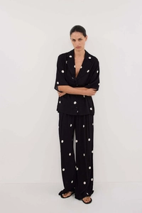Close-up of black chiffon two-piece set with white polka dots and wide-leg trousers