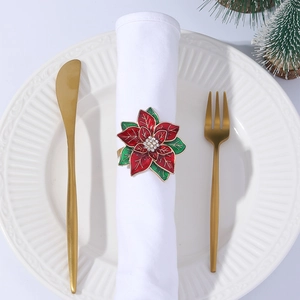 Festive Christmas poinsettia napkin ring with red petals and rhinestones on a white plate