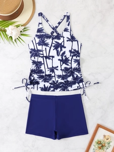 Flat lay of tankini swimsuit with palm tree print and drawstring details on marble background