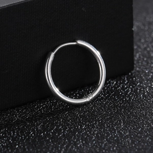 Close-up of a polished silver stainless steel hoop earring on a black textured surface