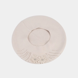 Detailed knit texture of beige beret featuring elegant floral applique and sparkly rhinestones
