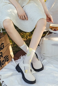 Detail of breathable mesh crew socks with yellow tulip patterns and Mary Jane shoes
