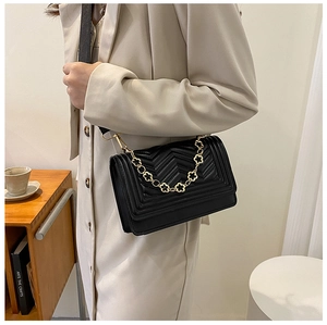 Detail of black chevron quilted handbag featuring gold flower chain and shoulder strap