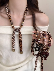 Detailed view of leopard print necklace with Saturn planet and heart-shaped charms