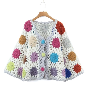 Handmade boho crochet cardigan with colorful floral patterns and rustic wood hanger