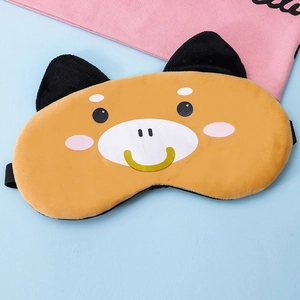 Close-up of a soft plush Shiba Inu sleep mask with elastic strap on a blue surface
