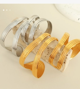 Macro detail of multi-line textured stackable cuff bracelets in gold and silver plating