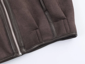 Detailed macro view of metal zipper and premium faux leather piping on dark brown jacket