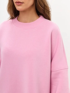 Detail of the ribbed crew neck and soft pink fabric texture of the oversized sweatshirt