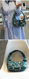 Close-up of a green Hobo bag featuring large gold rivets and glossy leather texture