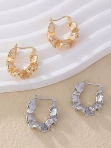 Detail of elegant gold and silver C-shaped hoop earrings with artistic pleated texture