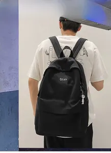 Detail of black canvas backpack with astronaut keychain and coolboy square woven label