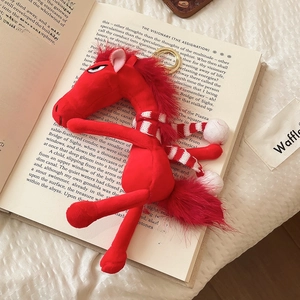 Detailed view of a red flocked horse keychain with a striped scarf on an open book