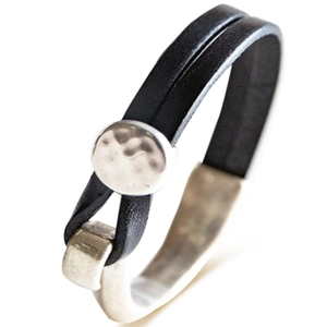 Dettaglio del bracciale in pelle nera con cuore e chiusura magnetica argentata