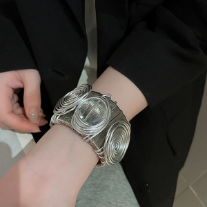 Macro shot of silver wire-wrapped cuff bracelet showing intricate swirl details