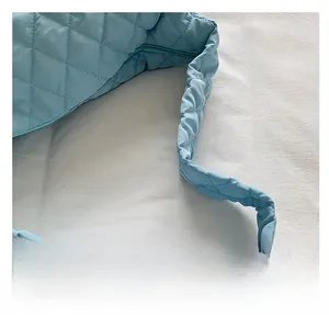 Close-up of padded quilted shoulder strap on a light blue fashion tote bag