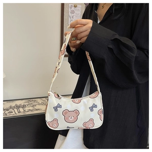 Close-up of white shoulder bag with pink bear print and blue bow detail on model
