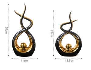 Detailed view of abstract ceramic statues with black glaze and golden orb accents