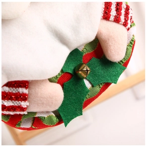 Close-up of Christmas gift bag featuring white plush, striped knit fabric and golden bell