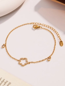 Detailaufnahme der goldenen Edelstahl-Fußkette mit Hohlblumen-Zirkonia und Anhängern