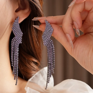 Close-up of elegant long tassel earrings with purple crystals and silver-tone settings
