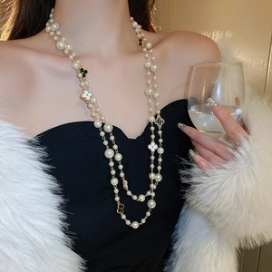 Close-up of double-layer long pearl necklace with black and white clover charms