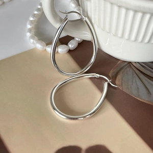 Detail of S925 sterling silver teardrop hoop earrings resting on a ceramic surface
