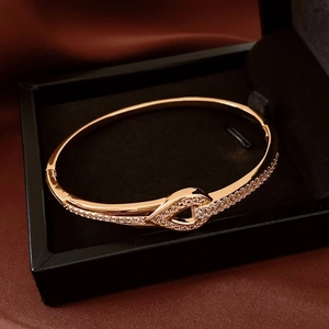 Détail du bracelet goutte évidé en or rose avec zircons blancs sur fond de soie fine