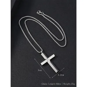 Polished stainless steel cross pendant necklace with geometric edges on a grey background