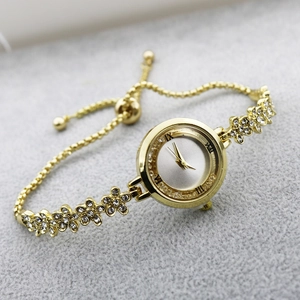 Detail of gold floral bracelet watch with crystals and silver dial on a plush surface