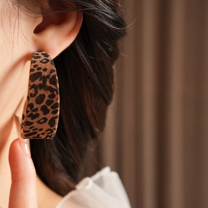 Close-up of a wide C-shaped leopard print earring with a soft flocked texture on ear