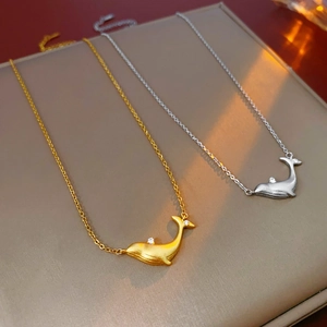 Detail of minimalist whale pendant necklaces in gold and silver with zircon stones