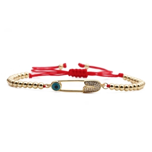 Adjustable red rope bracelet with golden beads and crystal paperclip charm in evil eye style