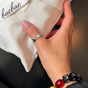 Minimalist double layer silver ring with twisted link chain design worn on thumb
