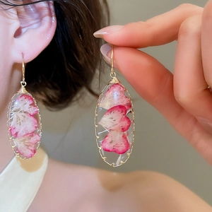 Una vista macro detallada de pendientes de resina con pétalos de flores secas rosas