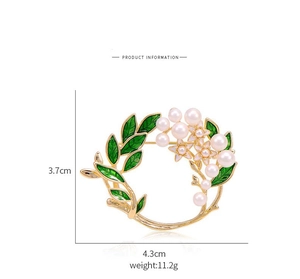 Detail of floral wreath brooch with pearls, green enamel leaves, and gold plating