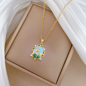 Macro detail of tulip pendant with blue enamel and crystals on a gold chain