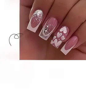Detail view of pink French press-on nails with white heart patterns and silver glitter