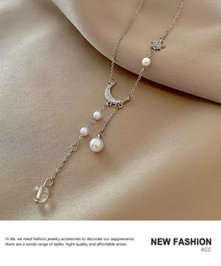 Close-up of silver moon and star pendant necklace with pearls on champagne silk fabric