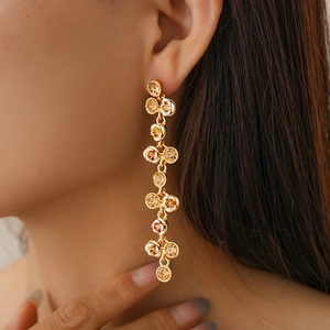 Gros plan de boucles d'oreilles à pompons dorés avec fleurs métalliques texturées