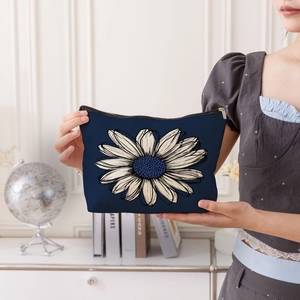 Navy blue cosmetic bag with white daisy floral pattern and secure zipper closure