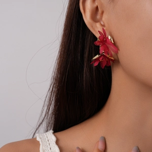 Detail of red chiffon petal earrings with gold center on a female model