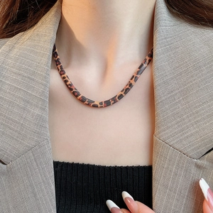 Nahaufnahme der flachen Schlangenkette mit Leopardenmuster an Model in beige Blazer