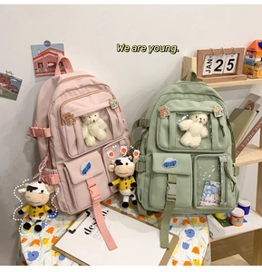 Dettagli di zaini per studenti rosa e verdi con tasche trasparenti e ciondoli di peluche