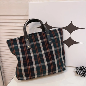 Detail of vintage plaid canvas tote bag with leather handles and gold rivet accents